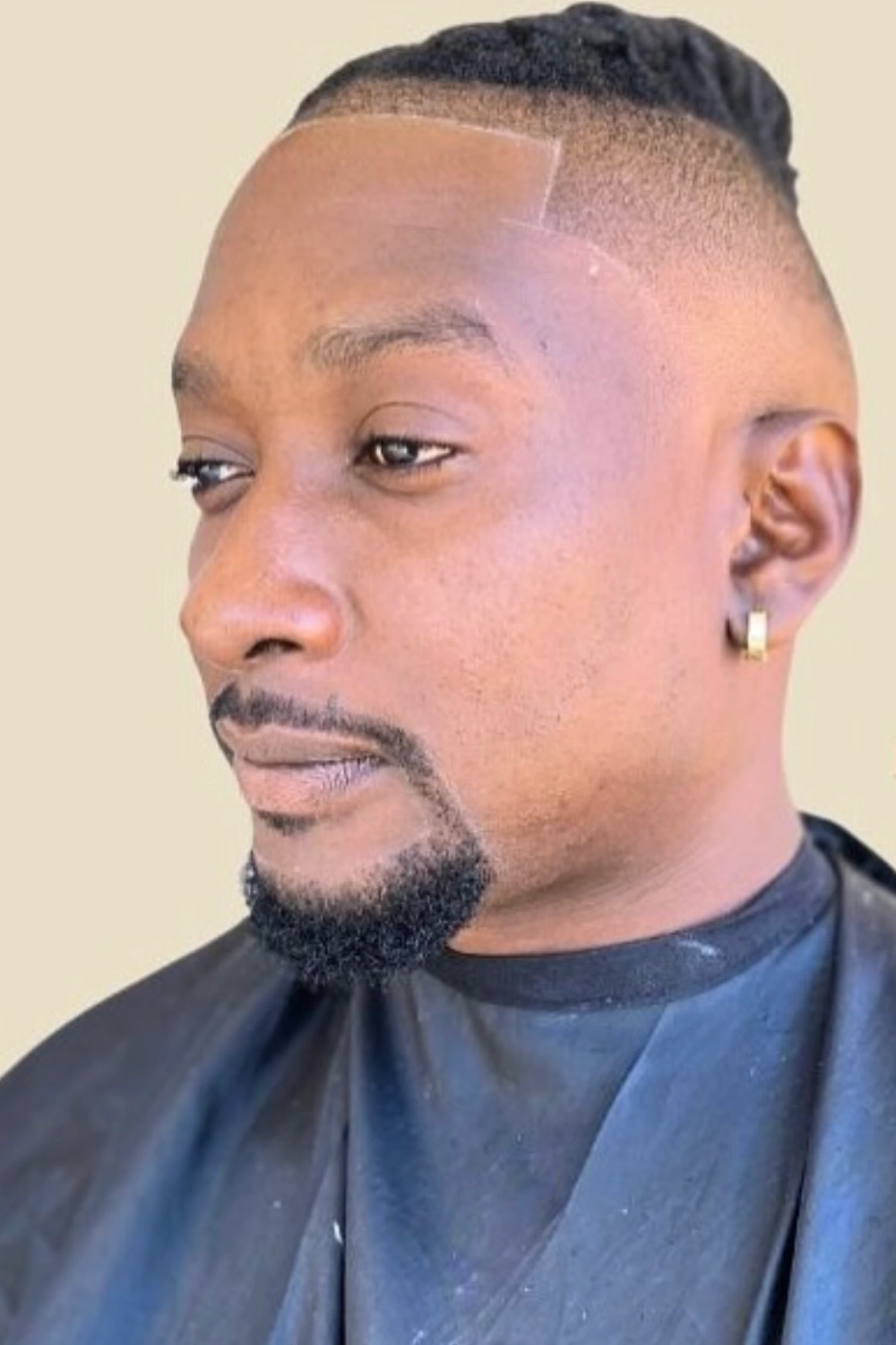 Side view of a client’s finished haircut with a defined hairline and shaped beard.